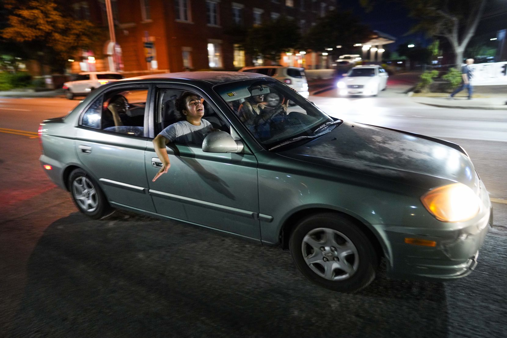 Protesters cheer from cars as they drive near the Dallas Police Headquarters during a...