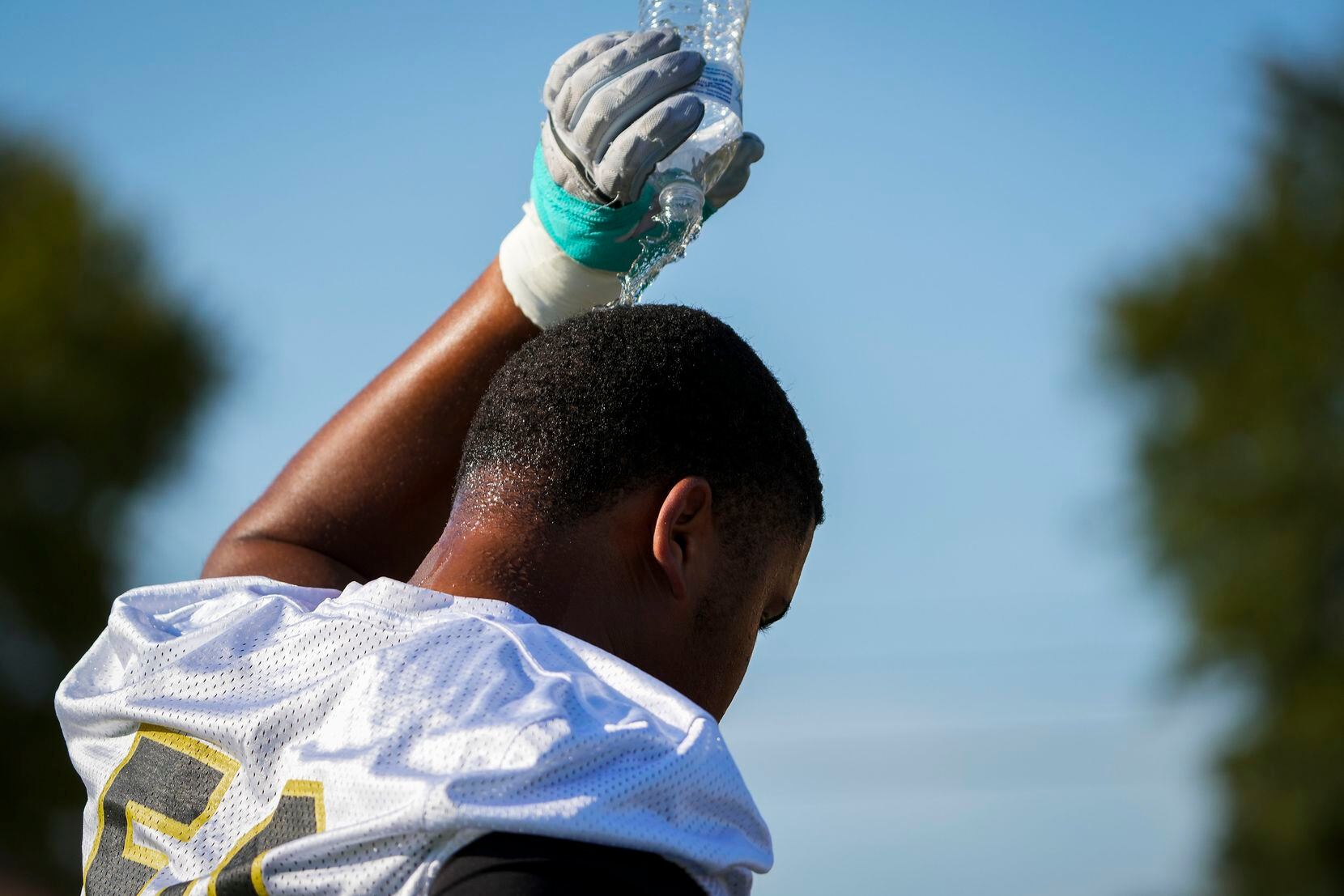 Lineman Jordan Smith-Rowe cools off pouring water over his head during the first practice of...