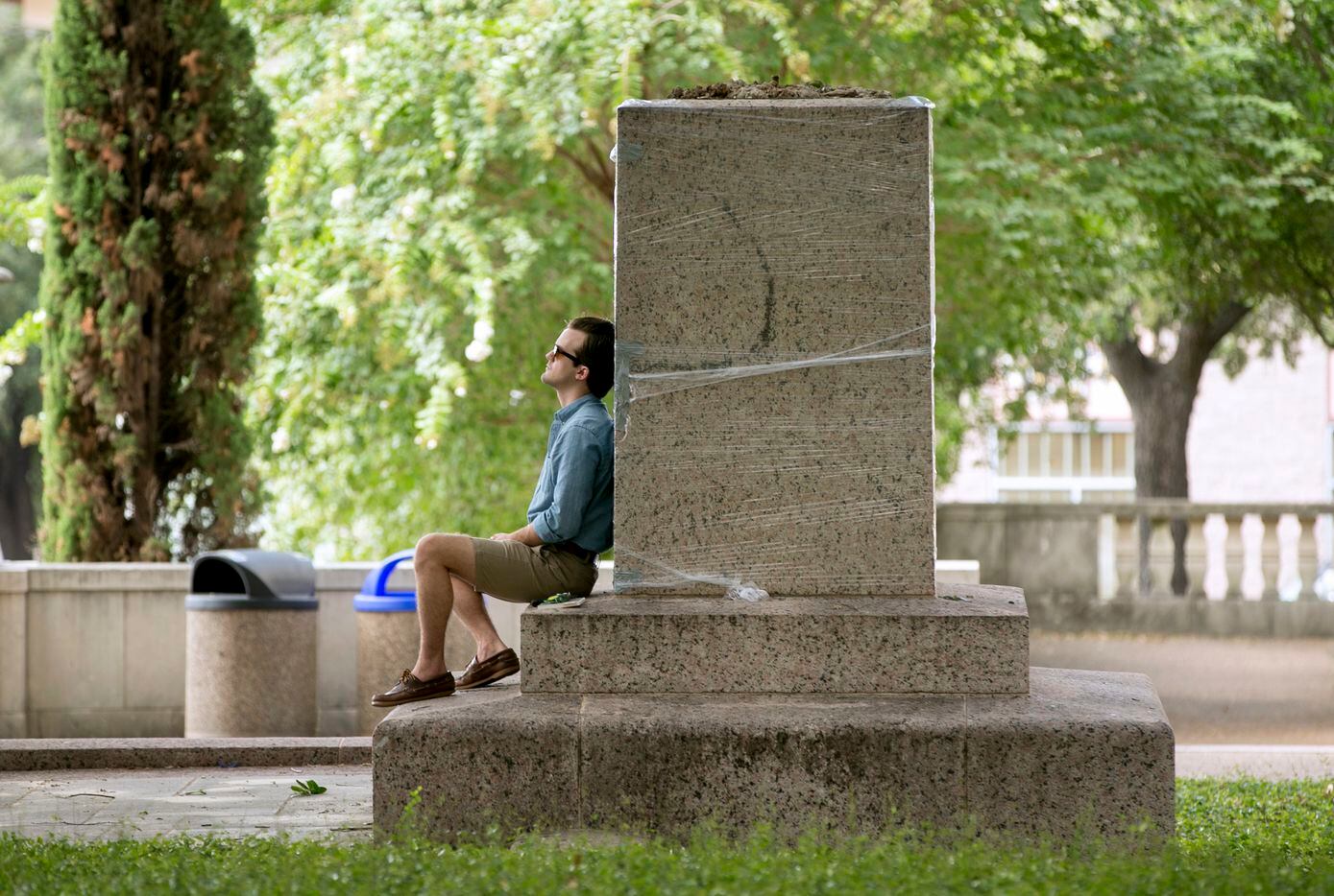 Edwin Bryan Robert Jr. sits at the base of a pedestal and "remembers history" after a statue...