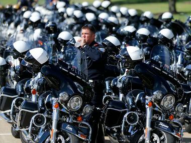 Colleyville motorcycle police officer Dustin Eason cools down with a drink of water as he...