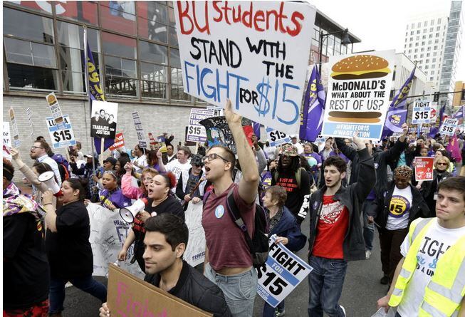  Boston University student Patrick Johnson, center, holds a sign as he joins with other...