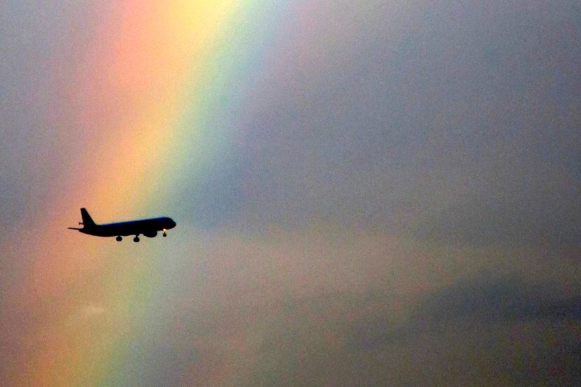 An American Airlines flight passes in front of partial rainbow on approach to landing at...