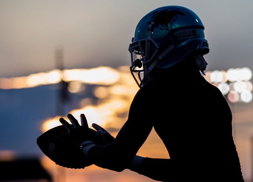 A Skyline football player catches a pass as he warms up before a high school football game...