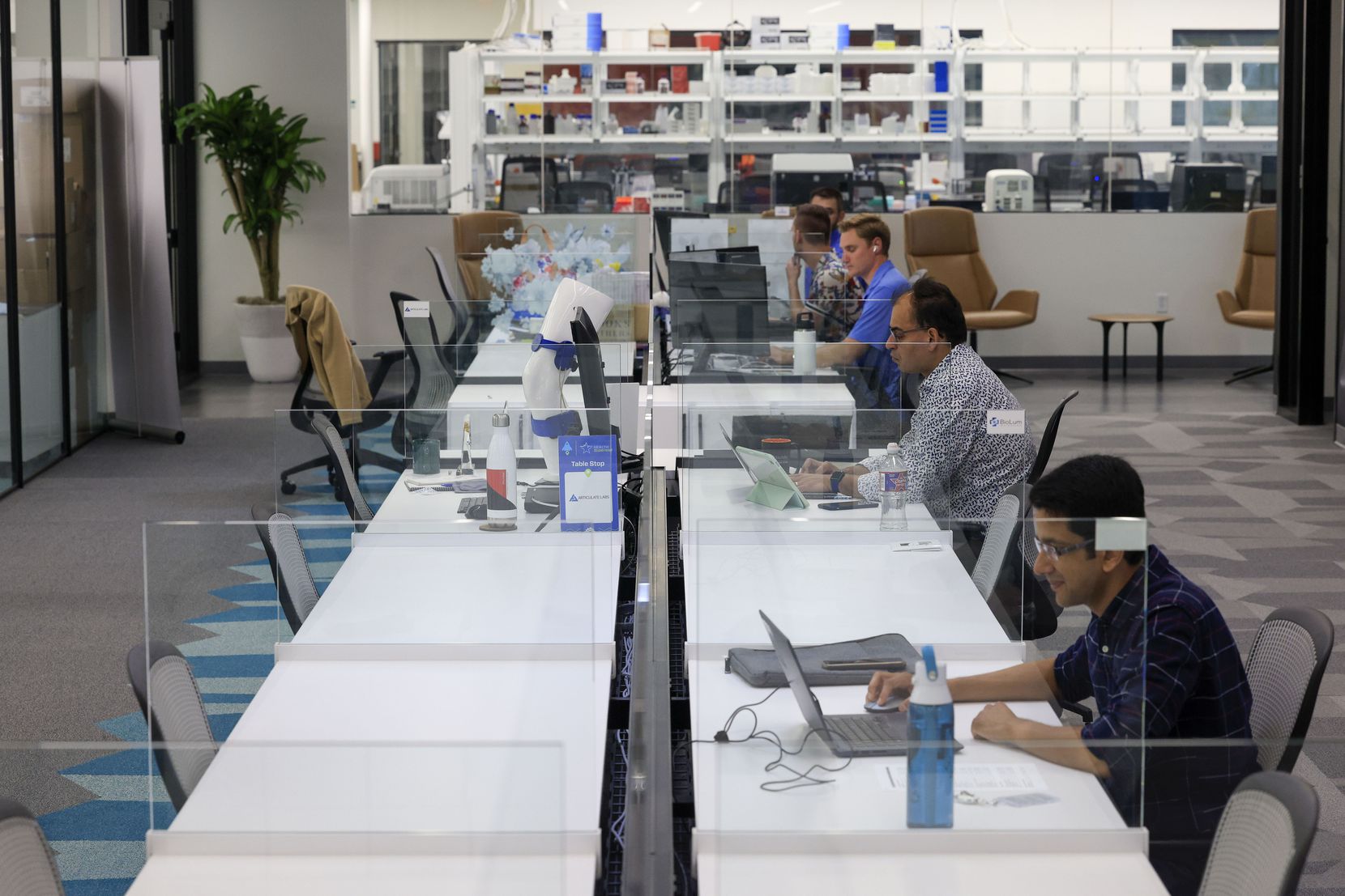 People work at desks at BioLabs co-working space in Dallas, Wednesday, July 6, 2022.