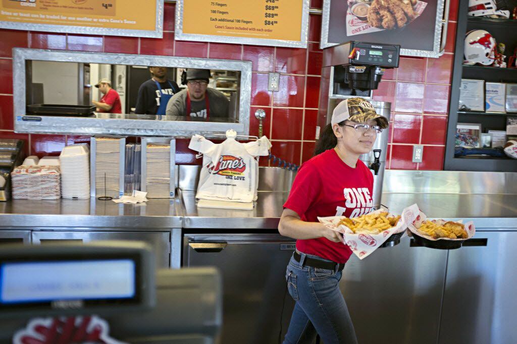 Marymar Gracia walks an order from the kitchen to a customer at a Raising Cane's Chicken...