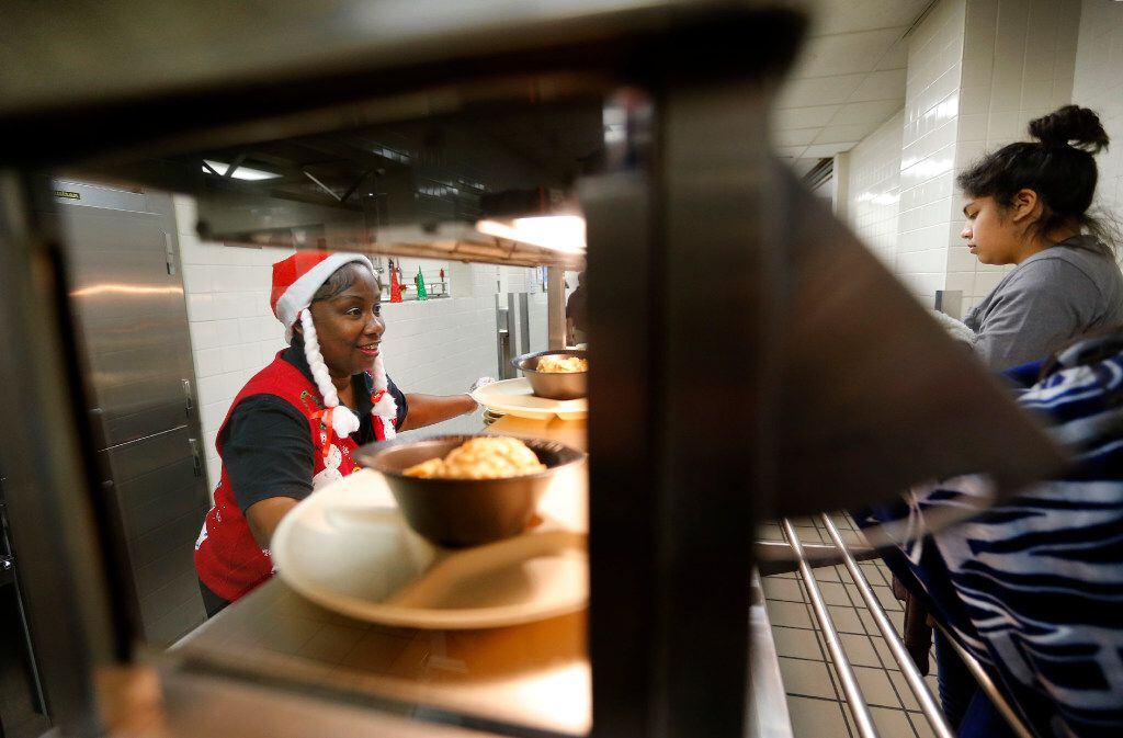 Line server Joyce Cummings (left) serves warm food to students at A. Maceo Smith New Tech...