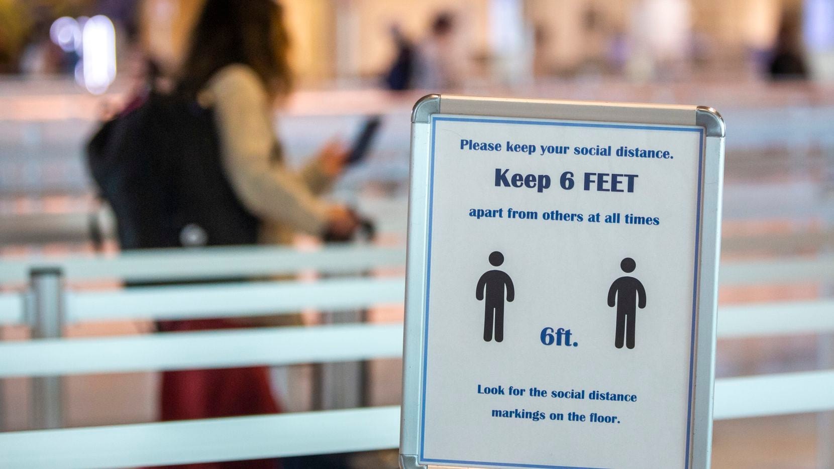 A passenger walks past a sign enforcing social distancing guidelines at Dallas Love Field...