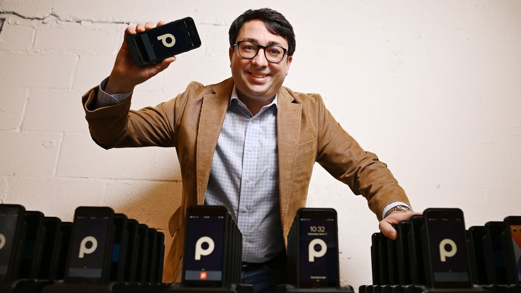 George Baker, founder, chairman and CEO of ParkHub, holds a point-of-sale device near a group of scanners at the company's offices in Dallas. The device can be used to sell or grant access into a parking or camping site.