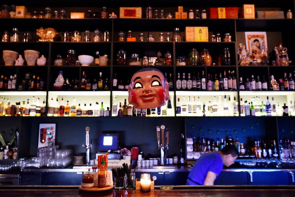 An Asian-style mask hangs from the ceiling over the bar inside the restaurant Hot Joy .