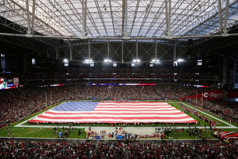 Una bandera estadounidense del tamaño del campo de juego es desplegada en el University of...