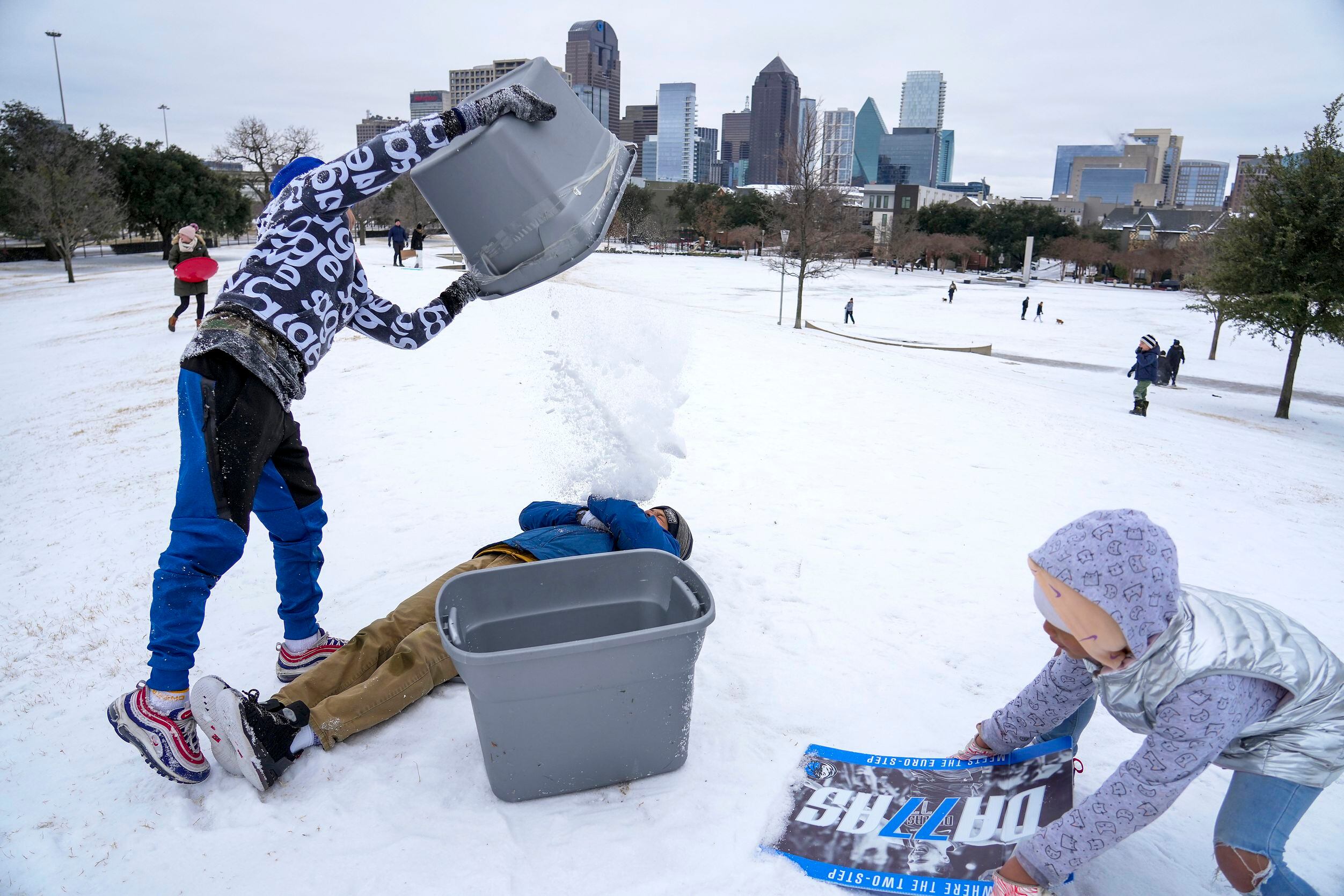 Mikie West, 14, has a bucket of snow dumped on him by his brother Mason, 12, as they play...