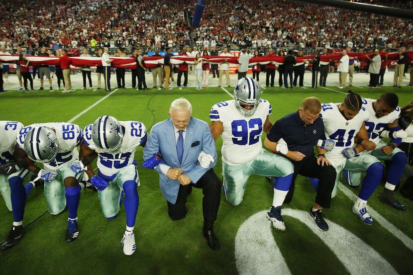 El dueño de los Cowboys de Dallas Jerry Jones se hinca junto a sus jugadores y entrenadores...