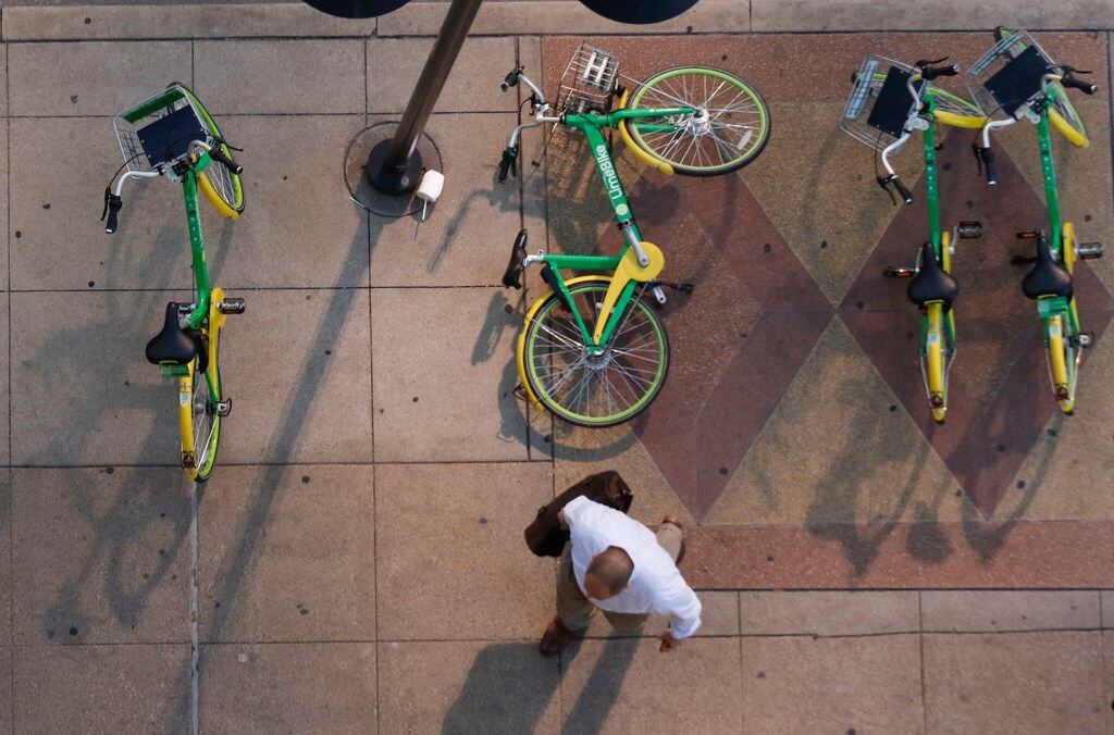 A pedestrian walks around a fallen rental bike at the corner of Harwood and Elm Streets in downtown Dallas.
