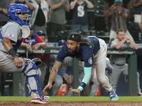 Seattle Mariners' J.P. Crawford right, dives to slide safely home past Texas Rangers catcher...