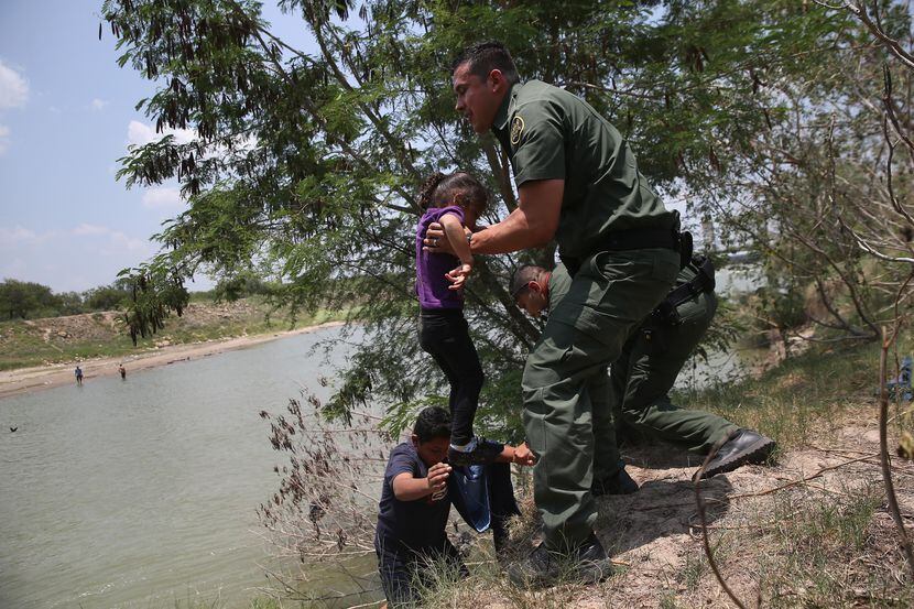 Un agente de la Patrulla Fronteriza ayuda a migrantes de El Salvador a salir del Río Grande...