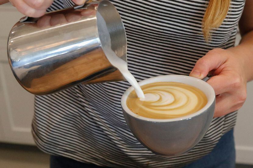 Barista Sara Hutson puts finishing touches on a plain latte at George Coffee + Provisions in...