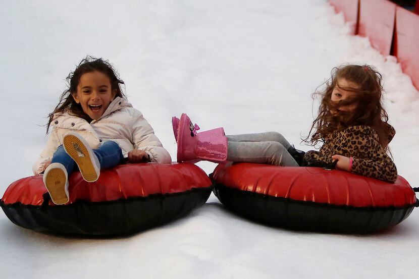 Kids tube down a snow hill at a festival.