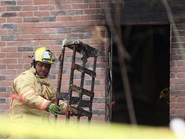 A Cedar Hill firefighter removes debris from a house that caught fire early Thursday...
