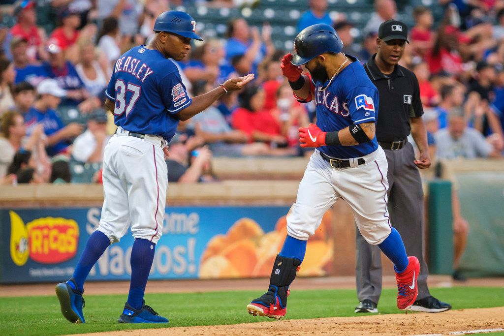 Texas Rangers second baseman Rougned Odor salutes third base coach Tony Beasley (37) as he...