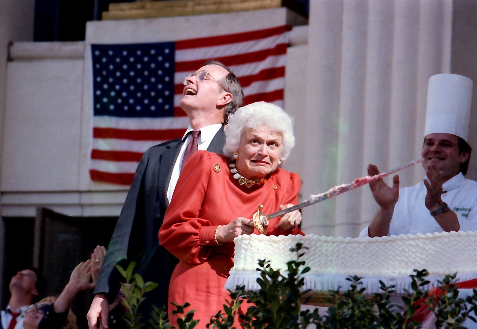 Barbara Bush cringes as a low-flying jet ceremonially passes overhead during cake-cutting...