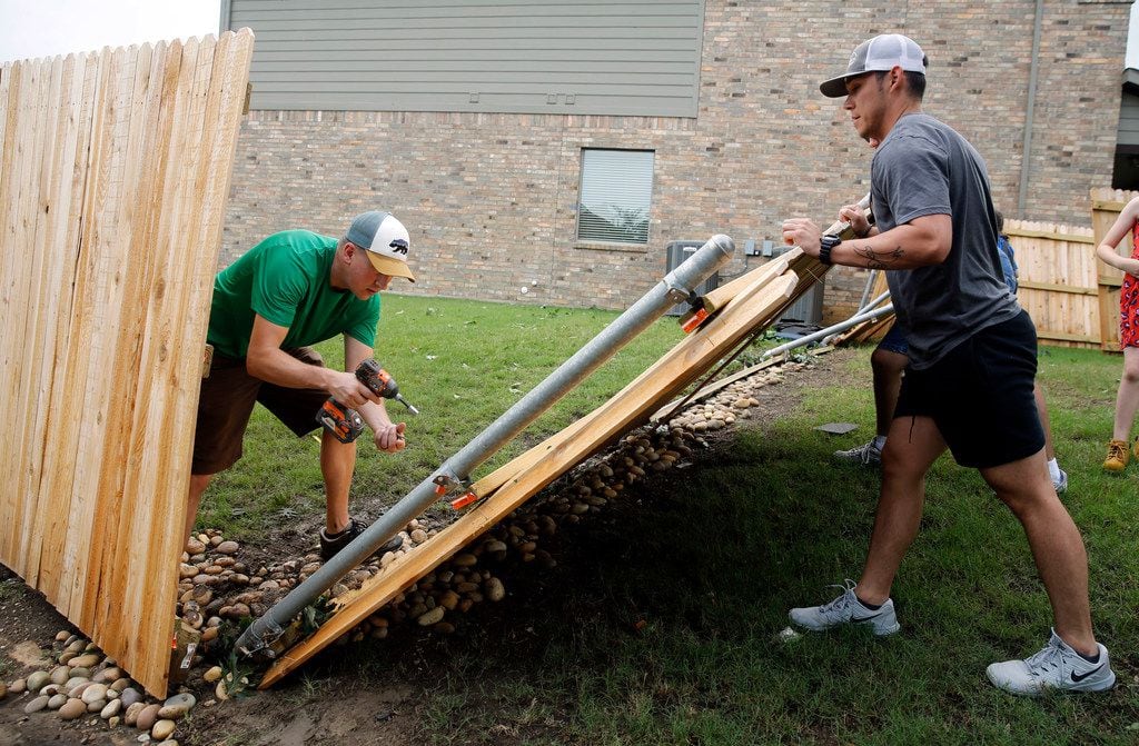 Fellow neighbors, including Jon Lambrecht (left), help remove a downed fence on Oliver Dr....