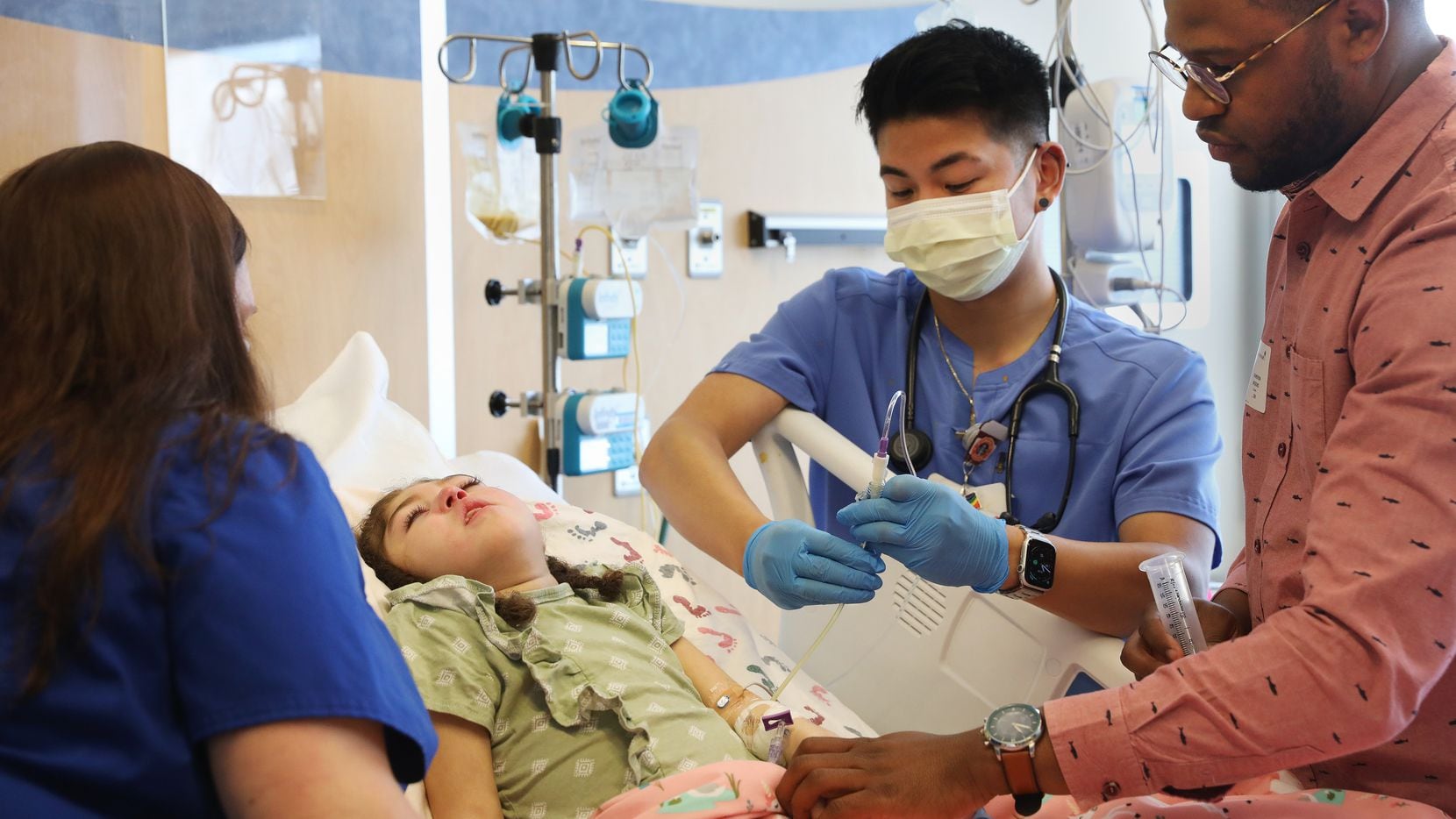 Charlotte Brooks, 5, is fed through a feeding tube by Savan Nguyen (center), R.N., while...