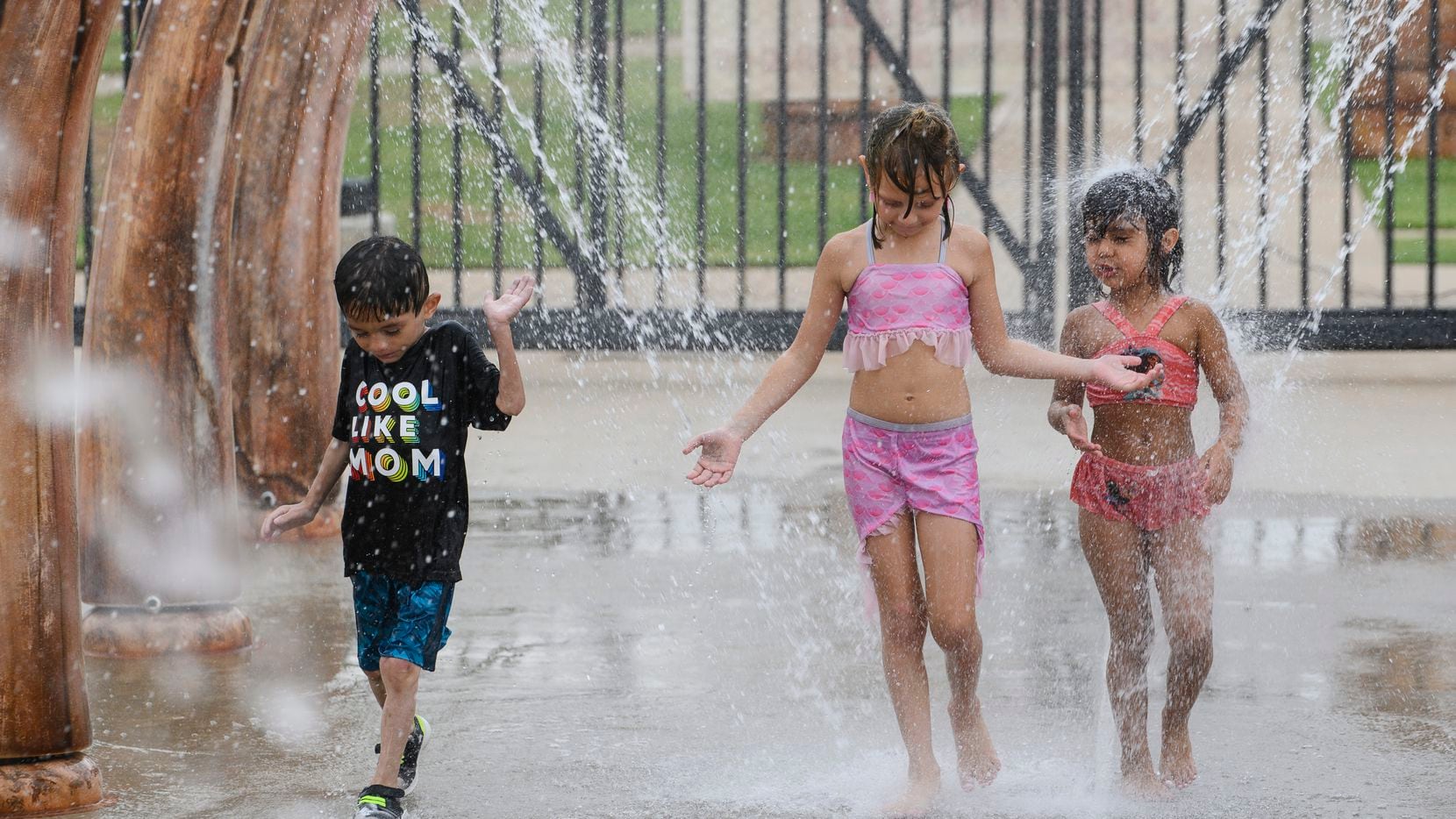 From left, Arturo Coca, 8, Maricla Coca, 7, and Madalyn Lange, 5, walk through a water...