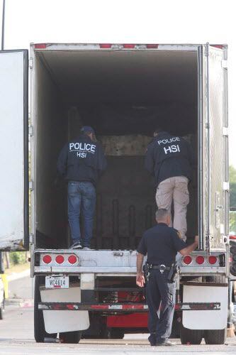 Unos agentes investigan el camión tráiler que iba cargado de indocumentados en el calor de...