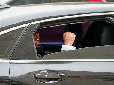 A passengers in a passing car lowers the window to yell support for as demonstrators march...