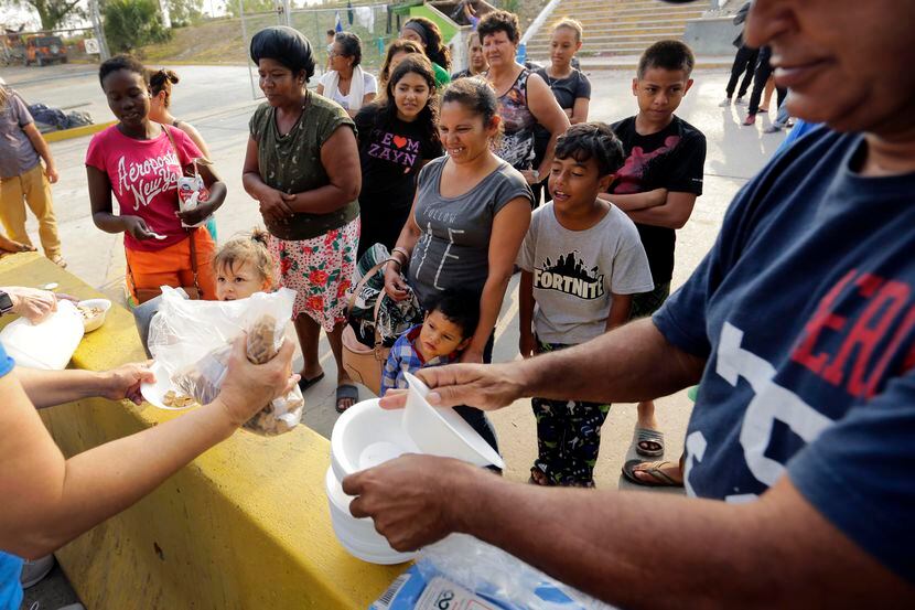 Migrantes de centroamérica reciben desayuno de parte de voluntarios cerca del puente...