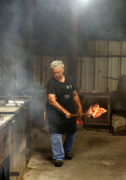 Tootsie Tomanetz makes her way between pits, hauling hot coals at Snow's BBQ in Lexington,...