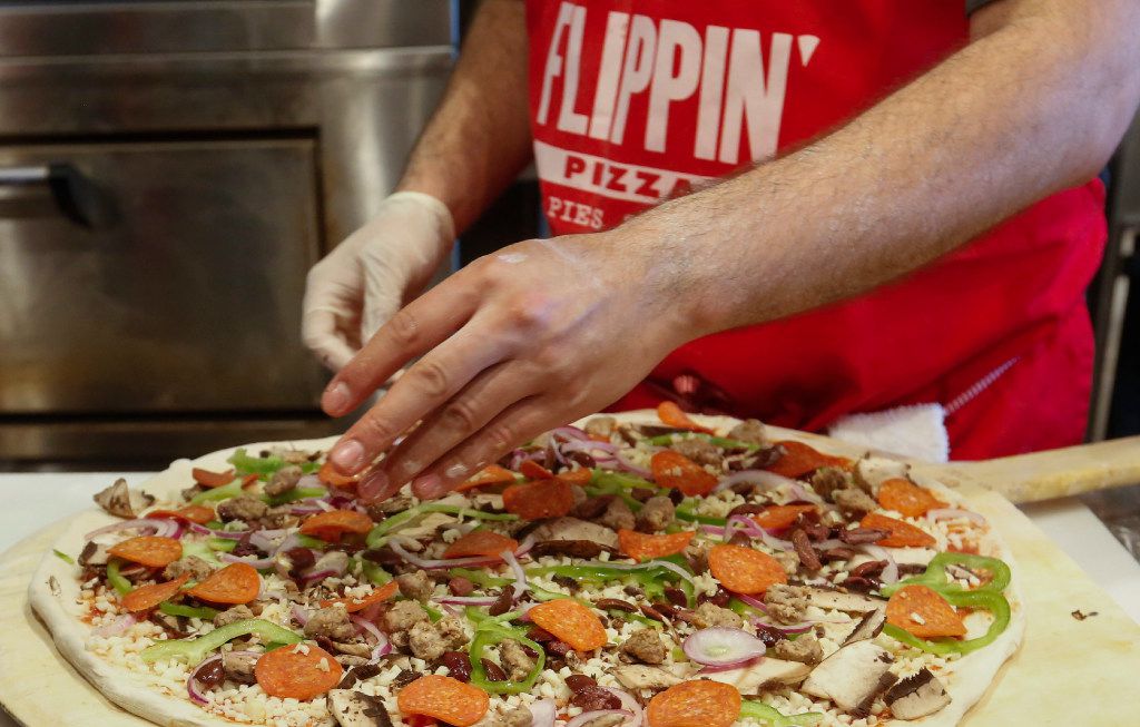 Carlos Osuna puts the finishing touches on a 18-inch pizza at Flippin' Pizza.  