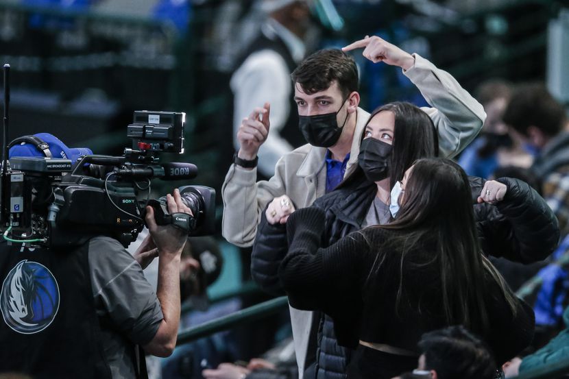 Seguidores de los Mavericks de Dallas saludan a una cámara de televisión durante el partido...