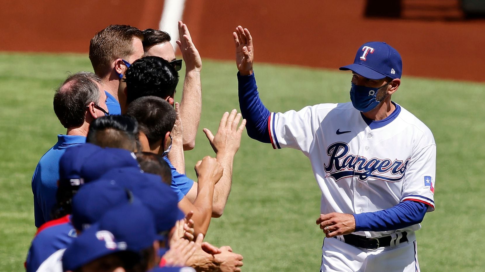 Texas Rangers manager Chris Woodward receives high-fives from his players during the team...