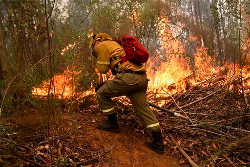 n bombero cava una zanja en un esfuerzo por detener el avance de un incendio forestal en la...