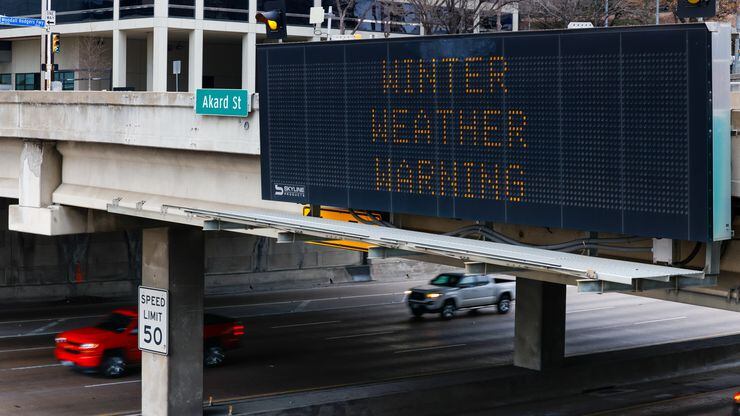 Winter weather warnings flash above traffic on Woodall Rodgers Freeway in downtown Dallas on...