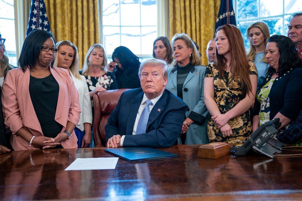 President Donald Trump is surrounded by guests during a ceremony where he signed the "Allow...