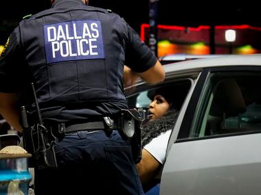Dallas police patrol a parking lot, checking on people in parked cars, in Deep Ellum on...