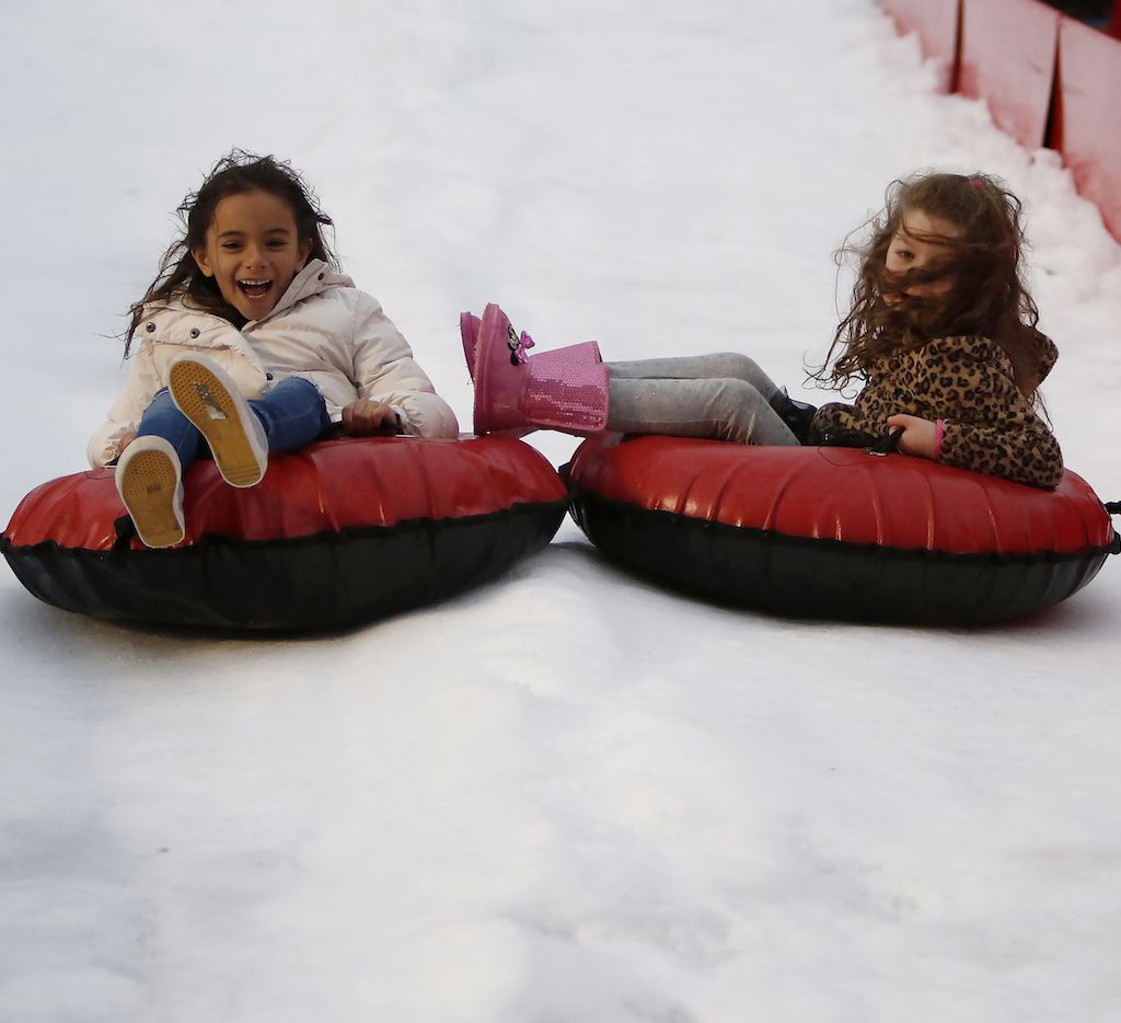 Kids tube down a snow hill at a festival.