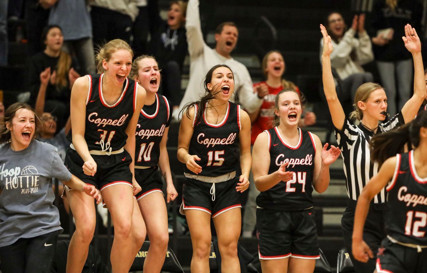 The Coppell High School woman’s basketball team bench reacts to the team scoring in the...