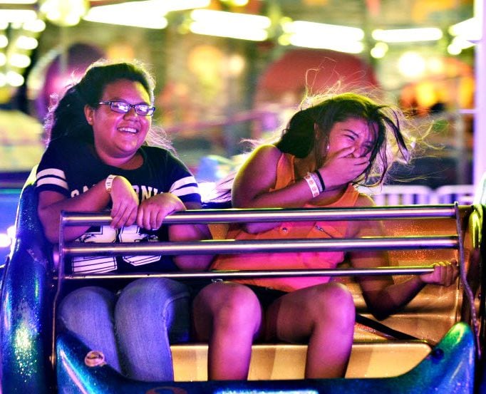Two girls laugh as they're tossed around on a carnival ride at the North Texas State Fair...