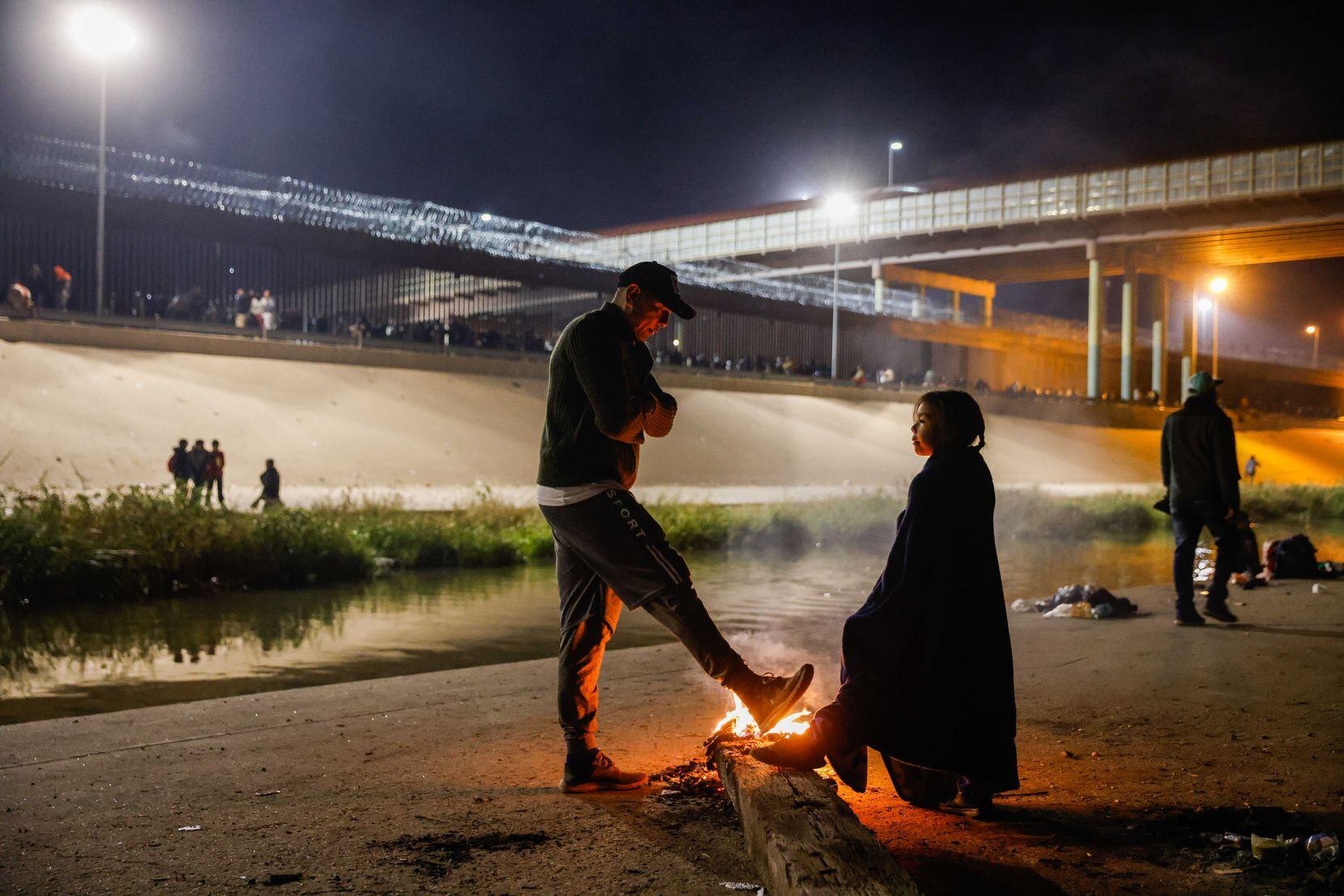 Blaidimar, 8, from Venezuela with another migrant, warm themselves with burning trash over a...