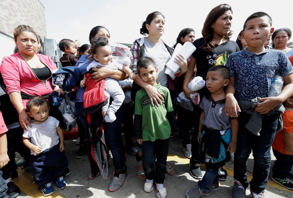 Immigrant women and children wait to enter the bus station after they were processed and...