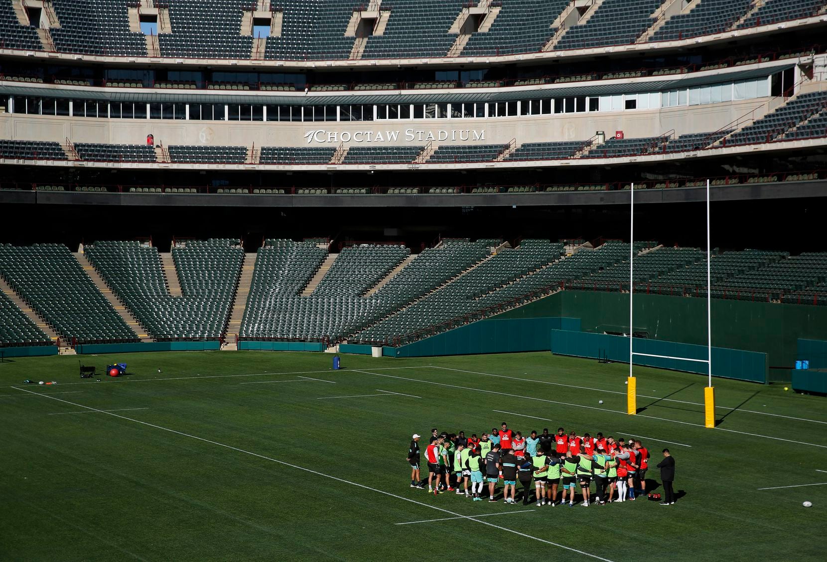 Members of the Dallas Jackals rugby team join arms during a break where they practice and...