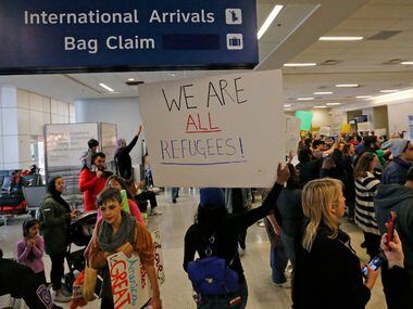 Protesters chant as they hold handmade signs at the international arrivals gate in Terminal...