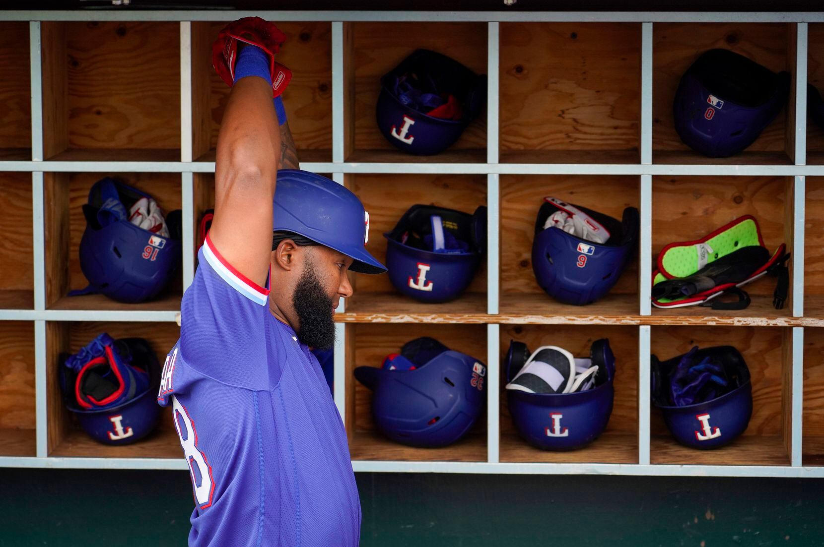 Texas Rangers outfielder Danny Santana stretches in the dugout before a spring training game...