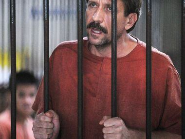 Alleged Russian arms dealer Viktor Bout talks to reporters as he stands in a temporary cell...