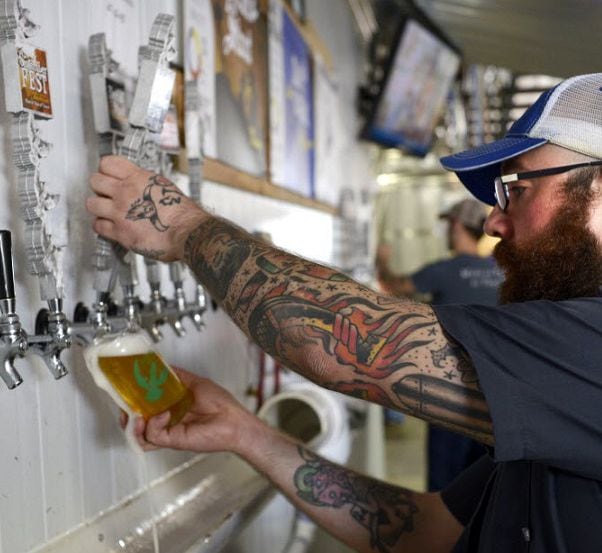 Volunteer bartender James Herrington pours a beer during a tasting and tour event at Martin...
