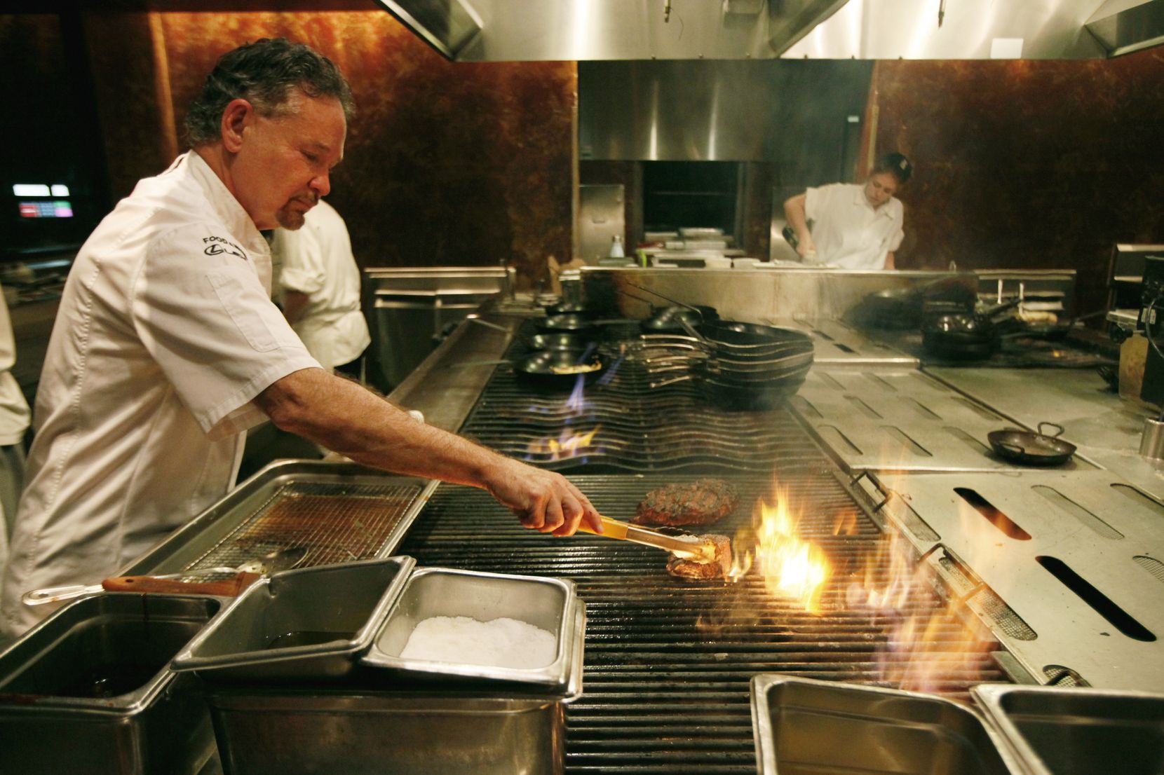 Chef Stephan Pyles grills a cowboy rib-eye steak while working the kitchen in the restaurant...