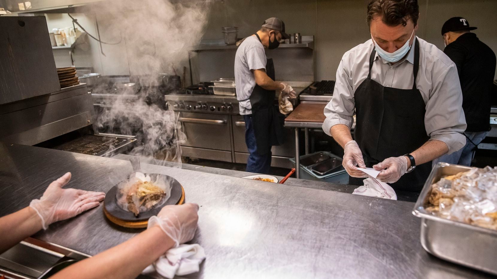General Manager Shane Ross (right) jumps behind the line to help plate dinner dishes for customers in the kitchen of Los Vaqueros Restaurant in in Fort Worth, Texas, on Saturday, March 13, 2021.